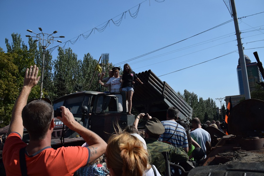 DESTROYED AND CAPTURED COMBAT VEHICLES were at the display in the square to raise the morale of the civilians. Here some women climb aboard a BM-21 rocket artillery launcher captured from the Kiev forces.