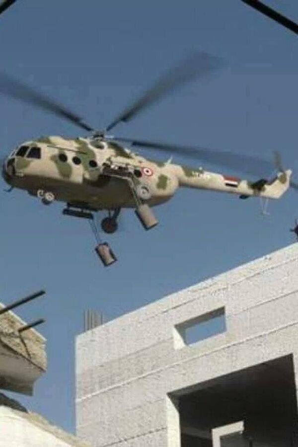 OLJEFATSBOMBER. Två syns här hänga i vajrar under en syrisk Mi-8 transporthelikopter som flyger över Aleppo. Bilden är troligen tagen 2013. Tunnbomberna saknar fenor då dessa tillkom senare i kriget för att kunna släppa dem med bibehållen någorlunda precision från högre höjd. Denna bild har flera gånger använts i propagandan mot Syrien då den placeras i kollage med döda och lemlästade civila från andra platser i Syrien. Foto: CankaoXiaoxi